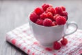 White Cup filled with fresh ripe raspberry on wooden background Royalty Free Stock Photo