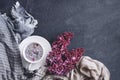 White cup with flowers on a saucer, a bouquet of lilac flowers and a blue drape striped scarf on a dark background Royalty Free Stock Photo