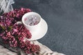 White cup with flowers on a saucer, a bouquet of pink lilac flowers and a blue drape striped scarf Royalty Free Stock Photo