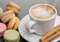 Coffee for breakfast. Multicolored macaroons, hot cappuccino, cinnamon tubes.