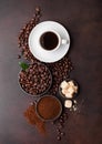 White cup of fresh raw organic coffee with beans and ground powder with cane sugar cubes with coffee tree leaf on brown background