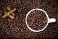 White cup full of coffee beans close up against the coffee beans background. Coffee mug. Royalty Free Stock Photo