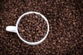 White cup full of coffee beans close up against the coffee beans background. Coffee mug. Royalty Free Stock Photo