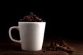 White cup full of coffee beans on the cloth sack in morning light and black background with copy space Royalty Free Stock Photo