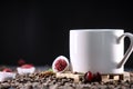 White cup full of coffee beans , red flowers and red chocolate candy against the black background. Morning espresso. Royalty Free Stock Photo