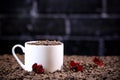 White cup full of coffee beans , red flowers and red chocolate candy against the background of a dark brick wall. Morning espresso Royalty Free Stock Photo