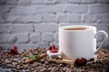 White cup full of coffee beans , red flowers and red chocolate candy against the background of a dark brick wall. Royalty Free Stock Photo
