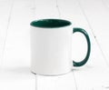 White cup with green inside on wooden background