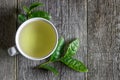 White cup of green tea with fresh tea leaves on wooden table Royalty Free Stock Photo