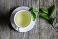 White cup of green tea with fresh tea leaves on wooden table, Royalty Free Stock Photo