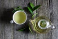 White cup of green tea with fresh tea leaves on wooden table Royalty Free Stock Photo