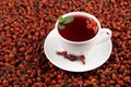 White cup of herbal hibiscus tea and dried rosehips against a background of dried rosehip berries. Close-up, selective focus