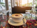 A white cup of hot cappuccino coffee with white mug topping and a glass of water, on glassed top black table decorated with Royalty Free Stock Photo