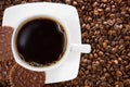 White cup of hot coffee on a background of brown beans Royalty Free Stock Photo