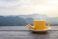 A white cup of hot espresso coffee mugs placed with cookies on a wooden floor with morning fog and moutains with sunlight Royalty Free Stock Photo