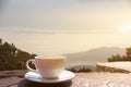 A white cup of hot espresso coffee mugs placed on a wooden floor with morning fog and moutains with sunlight background,coffee Royalty Free Stock Photo