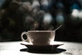 White cup with hot liquid and steam on black blurred background. Teaspoon in a cup. Tea and coffee concept. Royalty Free Stock Photo