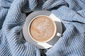 White cup of morning coffee on blue sweater background. Cozy home autumn concept. Aesthetics blog lifestyle. Still life