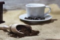 White cup and plate with beans, milling coffee and a wooden grinder on rustic background Royalty Free Stock Photo