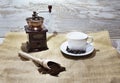 White cup and plate with beans, milling coffee and a wooden grinder on rustic background Royalty Free Stock Photo