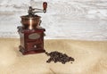 White cup and plate with beans, milling coffee and a wooden grinder on rustic background Royalty Free Stock Photo
