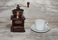 White cup and plate with beans, milling coffee and a wooden grinder on rustic background Royalty Free Stock Photo