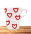 White cup with red hearts on wooden table isolated on white Royalty Free Stock Photo