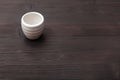 White cup for sake on dark brown wooden board