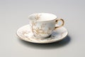 A white cup and saucer with a gold design. Imaginary oriental pottery.