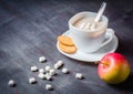 White cup on a saucer with hot cocoa. Morning breakfast. Dark wooden background.