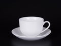 White cup on a saucer isolated on a black background. Royalty Free Stock Photo