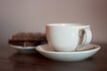 White cup on a saucer with metal spoon with chocolate biscuits