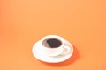 white cup with a saucer on a orange backgroundwhite cup of espresso with a foam on a orange background, selective focus Royalty Free Stock Photo