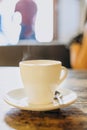 White cup with saucer and small spoon on a wooden table. Hot espresso in a white cup. Delicious coffee for breakfast in a cafe Royalty Free Stock Photo