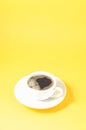 white cup with a saucer on a yellow background/white cup of espresso with a foam on a yellow background with copyspace Royalty Free Stock Photo