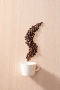 A white cup with smoke shape coffee beans on wooden background Royalty Free Stock Photo