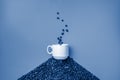 A white cup stands on a hill of coffee beans on a classic blue background Royalty Free Stock Photo