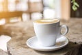 White cup with steaming hot cappuccino on the wooden table table with blurred background Royalty Free Stock Photo