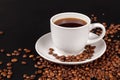 White Cup of strong coffee in roasted coffee beans, on a solid black background, foreground, close-up Royalty Free Stock Photo