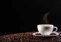 A white cup on a surface of coffee beans with the reflection of the sunrise in the coffee against a black background Royalty Free Stock Photo