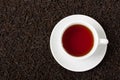 White cup of tea on black leaves texture brown background. Royalty Free Stock Photo