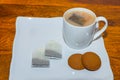 A white cup with tea or coffee along with cookies kept on a wooden table Royalty Free Stock Photo