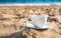 White cup with tea or coffee on sand beach front of sea Royalty Free Stock Photo