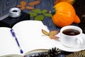 A white cup of tea coffee on a wooden background. Ripe pumpkin. Cones and leaves on a wooden table. Open notebook Royalty Free Stock Photo