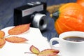 A white cup of tea coffee on a wooden background. Ripe pumpkin. Cones and leaves on a wooden table. Open notebook Royalty Free Stock Photo