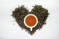 A white cup of tea on the dried tea leaf in the heart shape Royalty Free Stock Photo