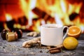 White cup of tea with lemon, ginger, orange, jam and medical mask against the background of a burning fireplace.Healthcare.