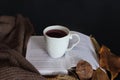 Cup of tea on book and autumn decorated black desk with copy space