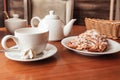 White cup, tea pot and croissant on table in cafe Royalty Free Stock Photo