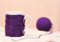 White cup with violet knitted thing on